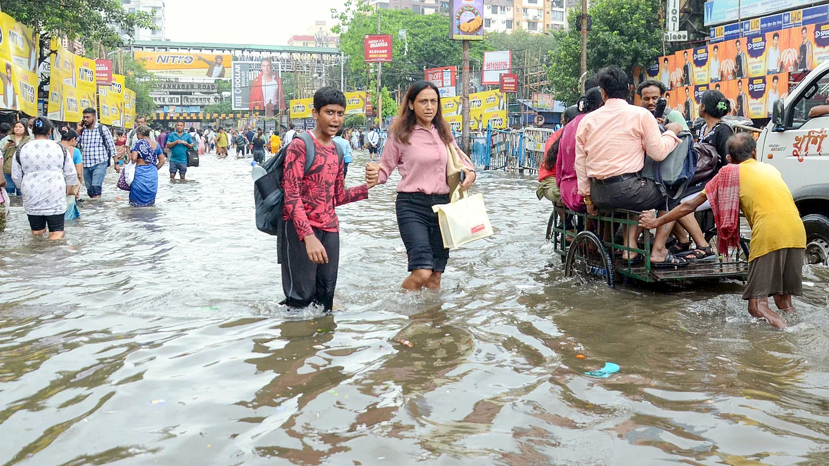 Commuters navigate a waterlogged street in Kolkata