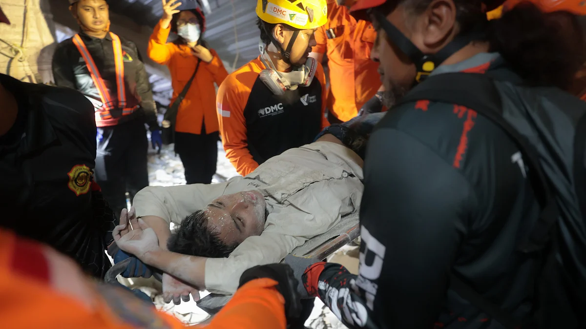 Rescuers pull out a survivor from the collapsed building