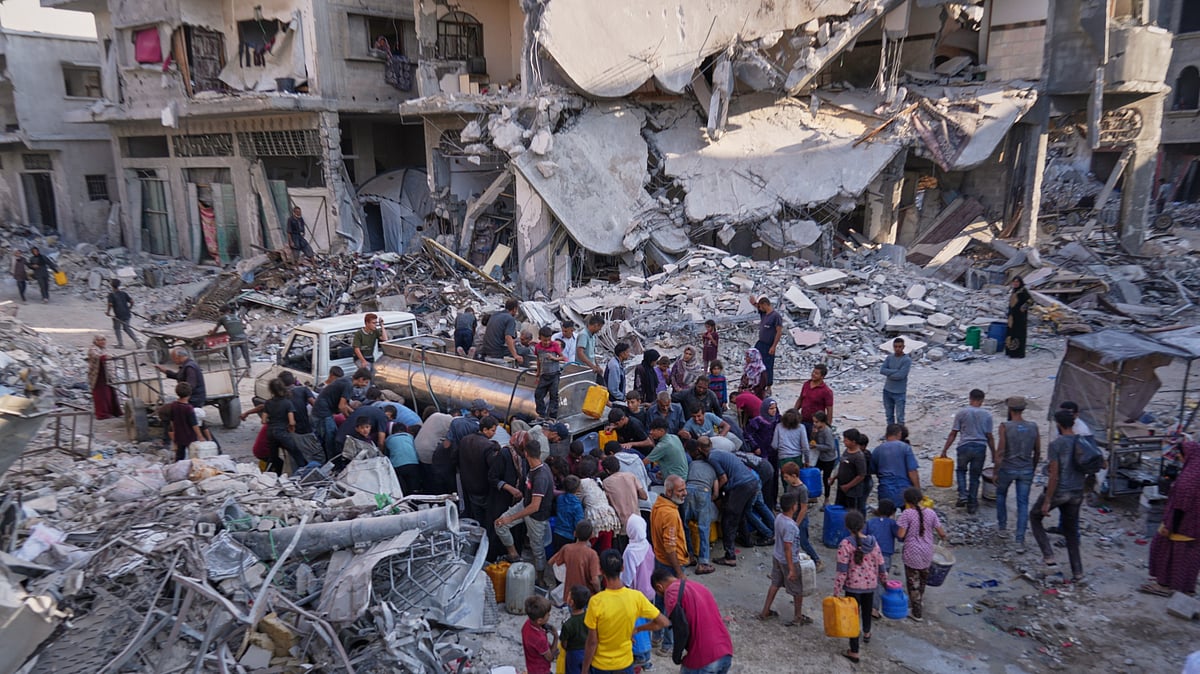 Palestinians collect water from a truck amidst devastation in Gaza City.