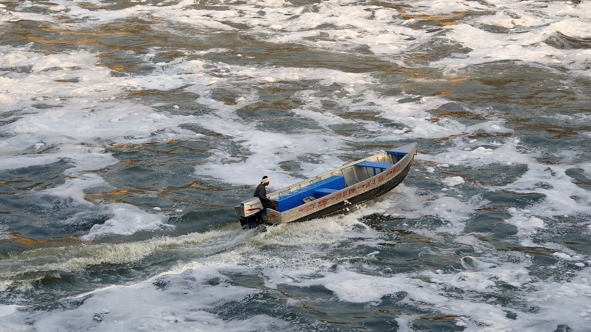 A worker sprays chemicals on toxic foam floating over the Yamuna in New Delhi.