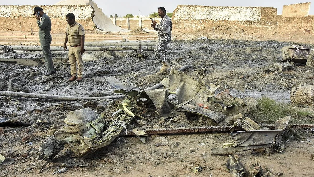 Police and IAF personnel stand amid charred debris
