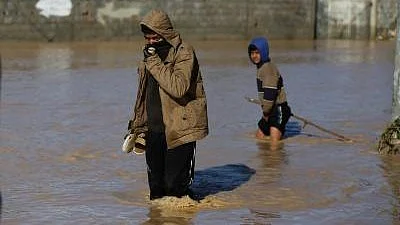 Palestinians wade through knee-deep floodwaters in Gaza.