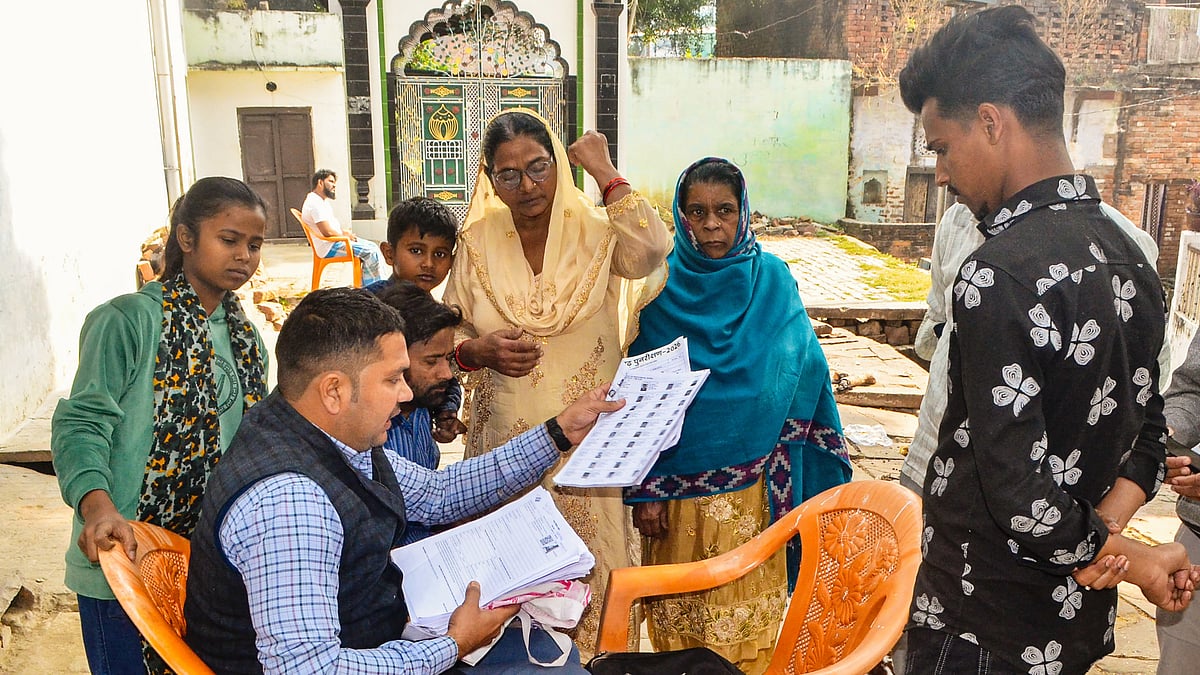 A BLO explains details of enumeration forms to voters for the SIR in Mirzapur, Uttar Pradesh