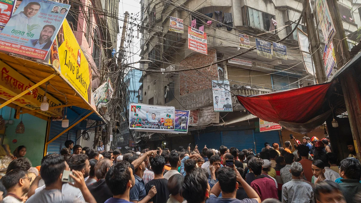 Crowds pack a narrow Old Dhaka lane after a quake collapses a roof and wall.