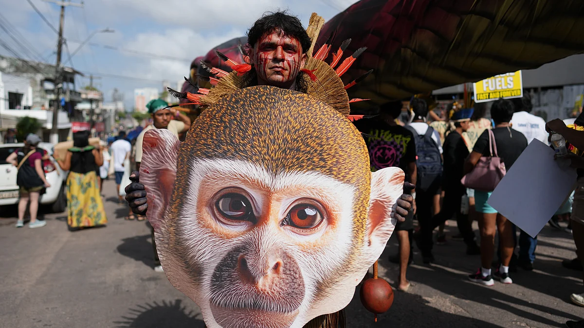 An Indigenous activist carries an image of a monkey at a climate protest during the COP30.