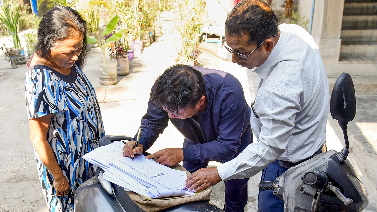 A BLO assists residents in completing their electoral forms.