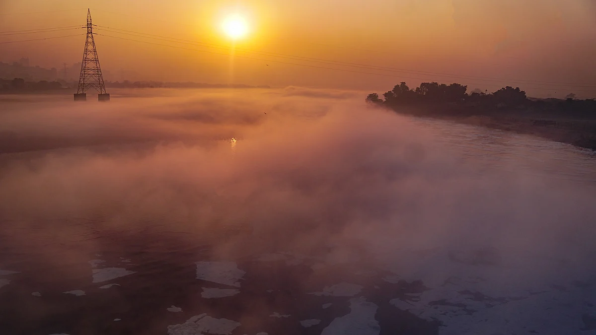 Fog-shrouded Yamuna draped in toxic foam on a winter morning in New Delhi.