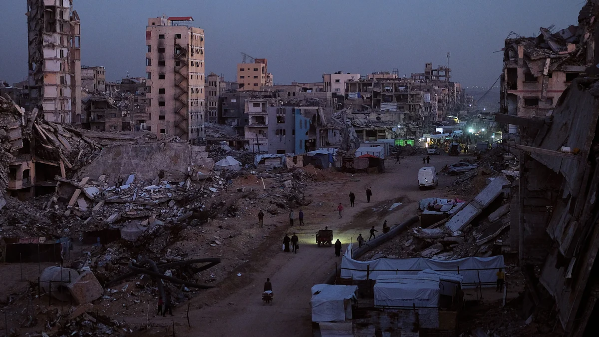 Palestinians pick their way through the wreckage of Al-Karama in Gaza City.