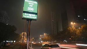Vehicles pass an AQI monitor showing 506 on Barakhamba Road, New Delhi.