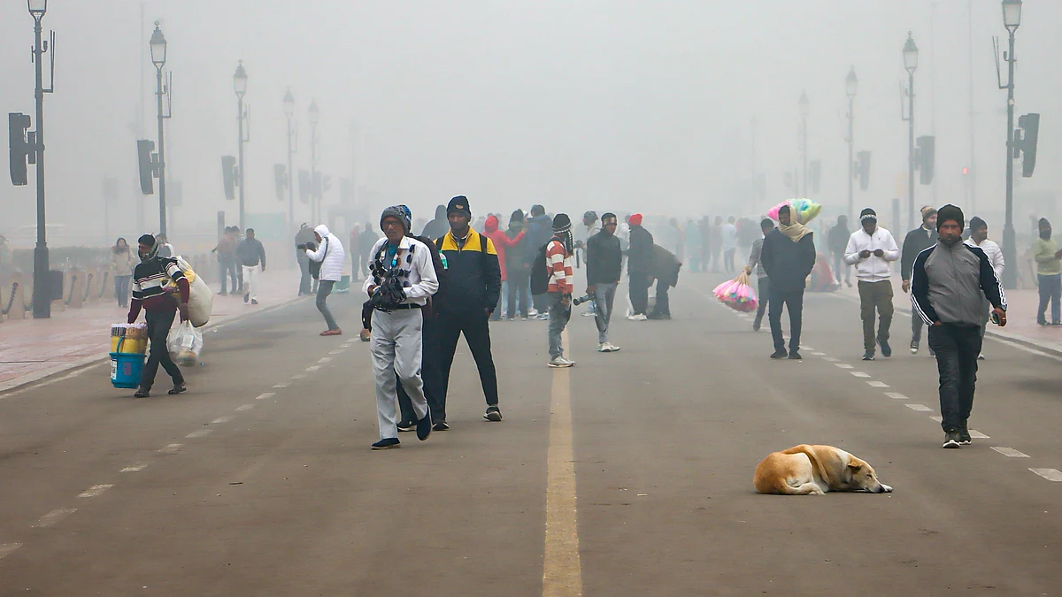 People walk along Kartavya Path amid smoggy winter skies in New Delhi.