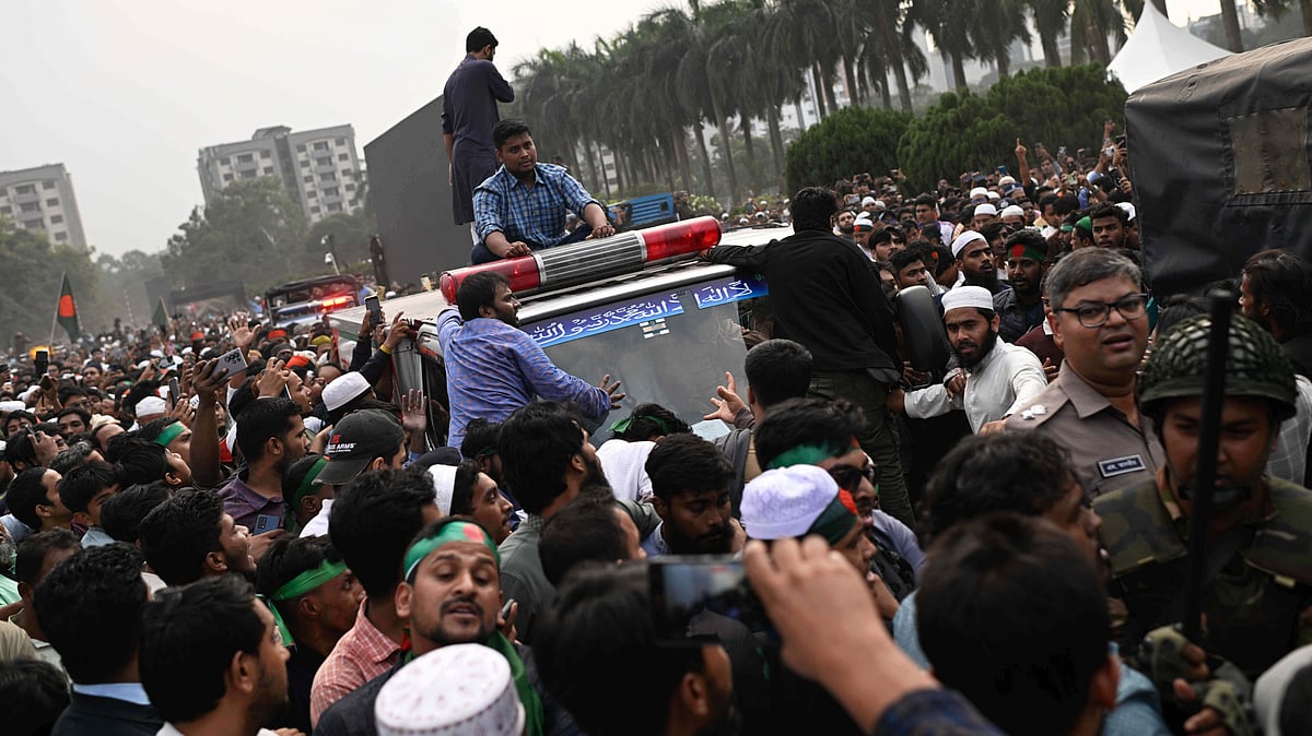 People gather around an ambulance carrying the body of Sharif Osman Hadi in Dhaka.