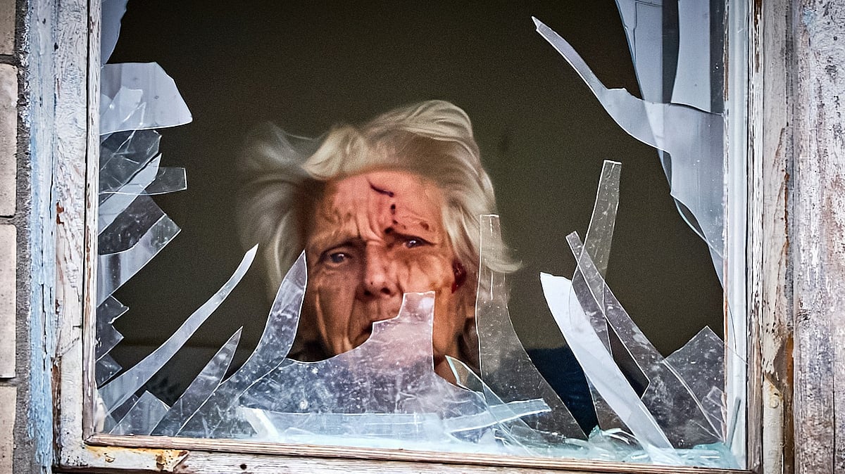 An injured woman looks out of her window in a building hit by a Russian drone in Kyiv, 23 Dec
