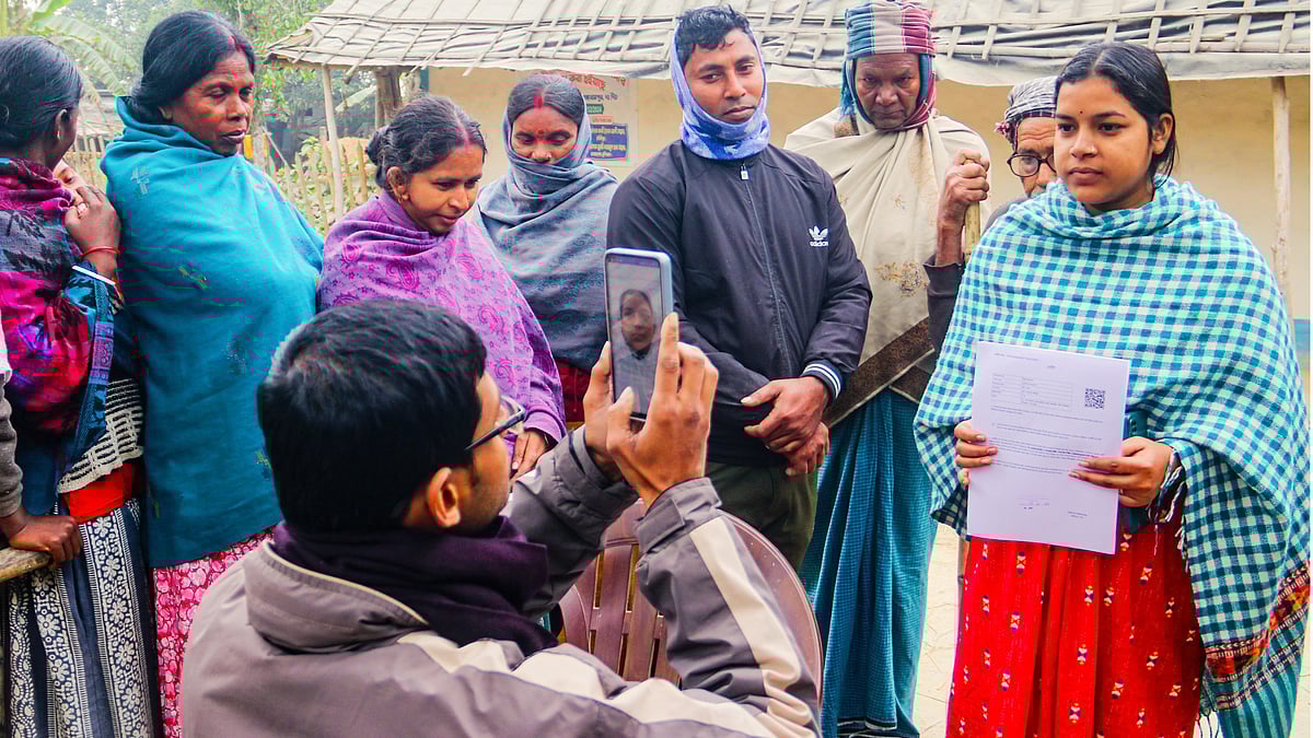 A BLO photographs a voter after handing over a hearing notice, in Dakshin Dinajpur, West Bengal.