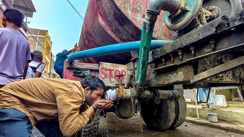 A resident drinks water from a municipal tanker in Indore.