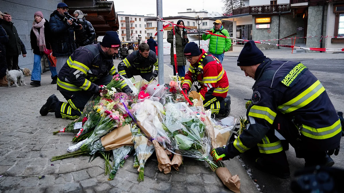 Firefighters lay flowers near the sealed off Le Constellation bar in Crans-Montana, Switzerland