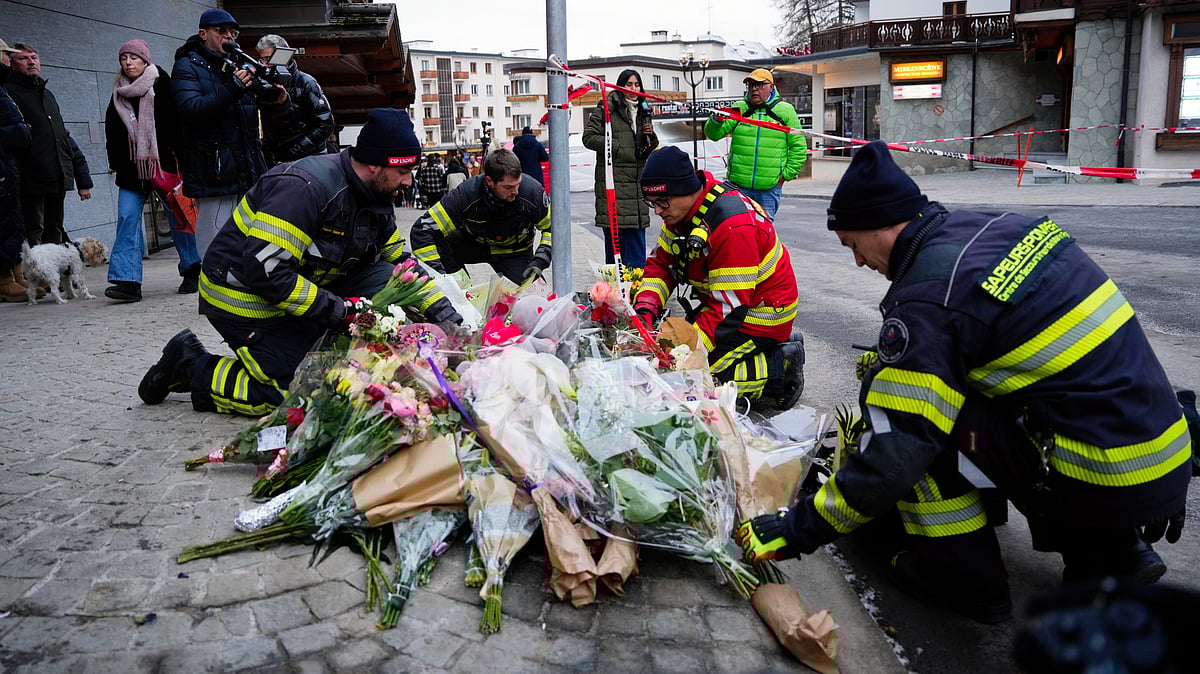 Firefighters lay flowers near the sealed off Le Constellation bar in Crans-Montana, Switzerland