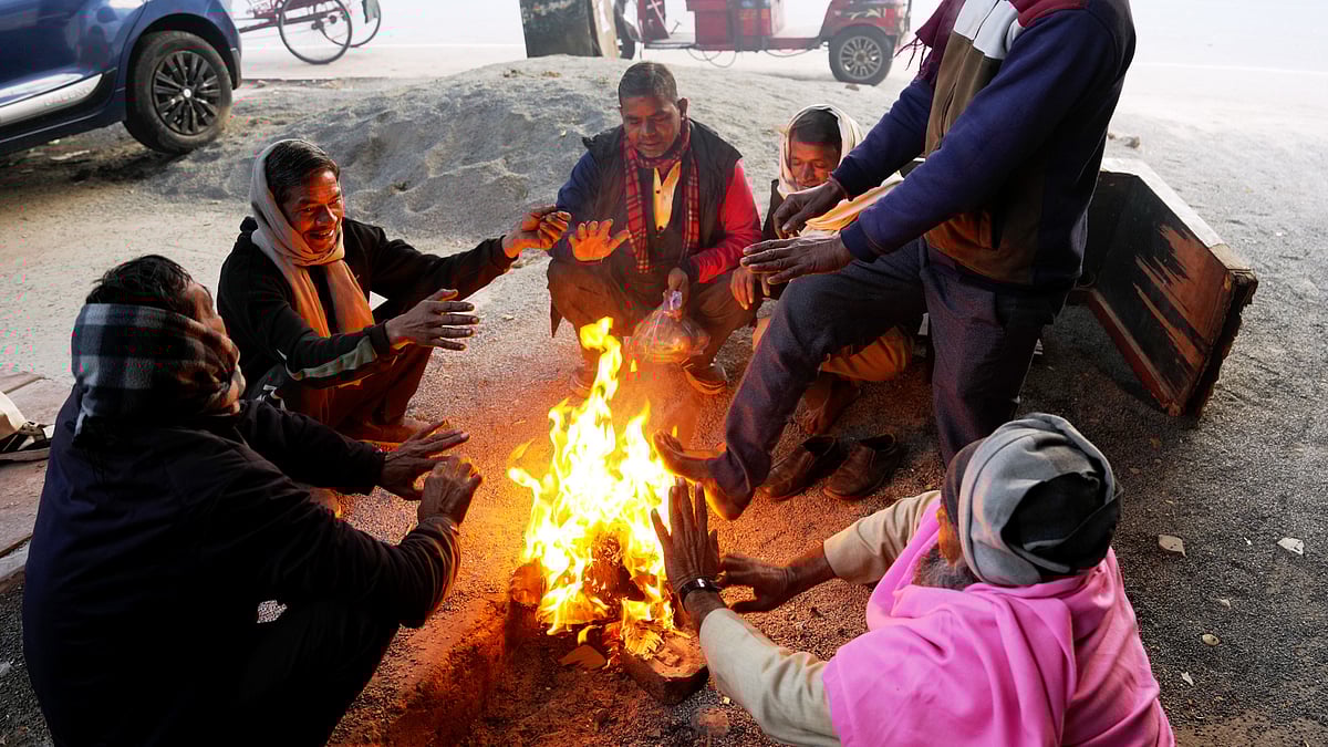 People huddle around a small fire to keep warm as biting cold grips New Delhi.