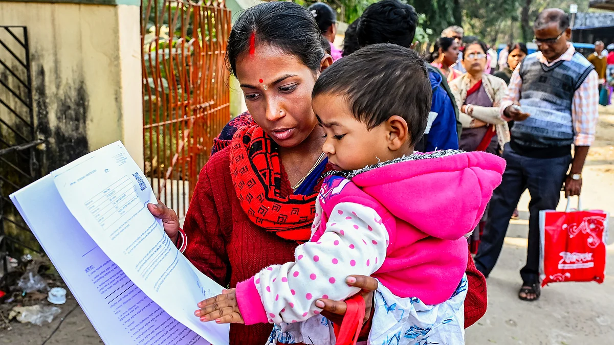 A woman carries a toddler as she waits to be enrolled, in Nadia, West Bengal, 14 Jan