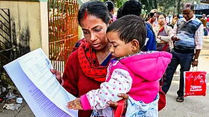 A woman carries a toddler as she waits to be enrolled, in Nadia, West Bengal, 14 Jan
