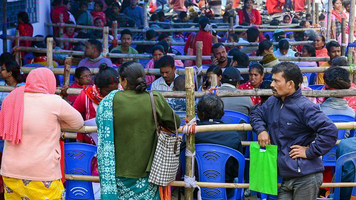 People wait in queues at a centre during SIR hearings, in Balurghat, West Bengal