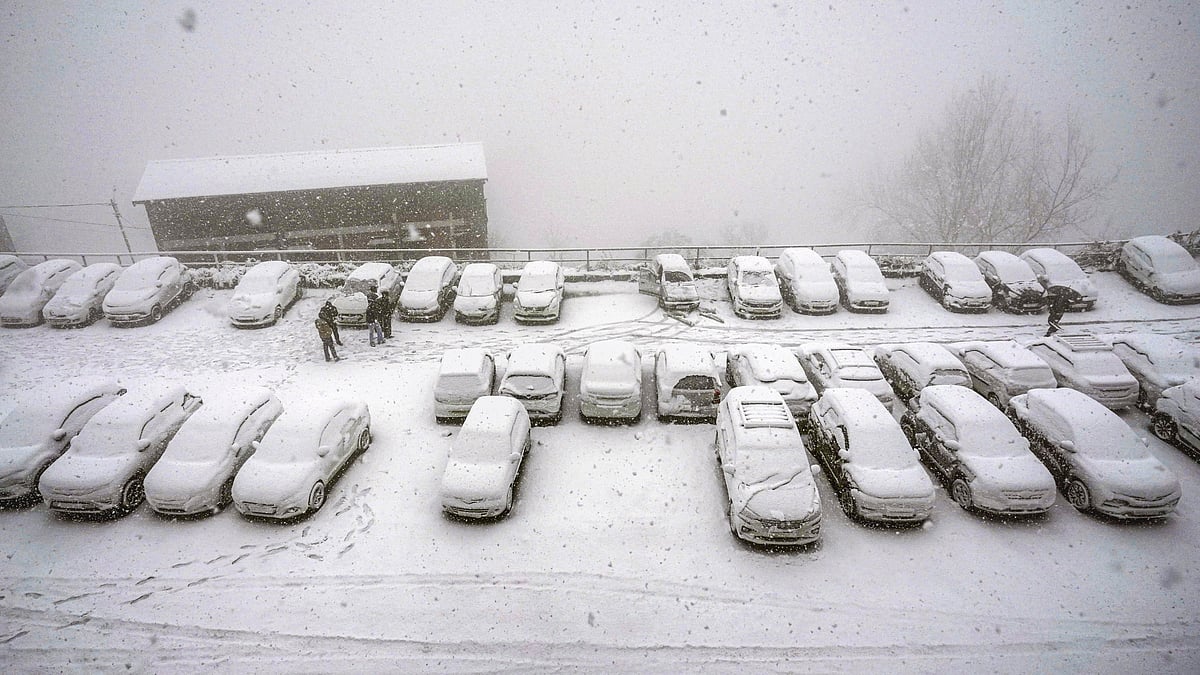 Vehicles lie covered under fresh snow at a parking area in Shimla