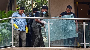 Forensic team members remove a shattered glass pane from the balcony of filmmaker Rohit Shetty.
