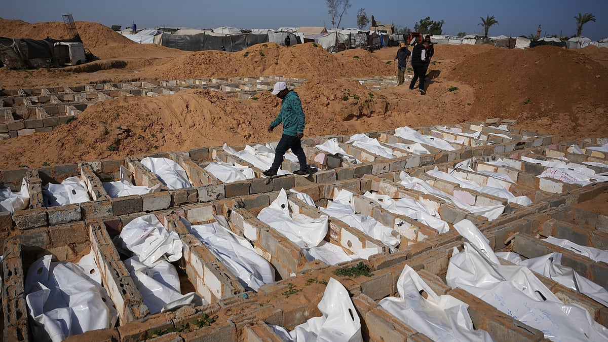 A man passes freshly dug graves holding the bodies of unidentified Palestinians.