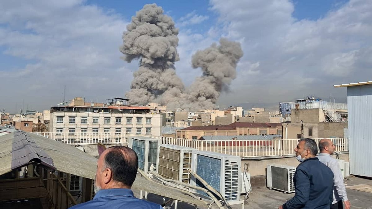 People watch as smoke rises on the skyline after an explosion in Tehran.