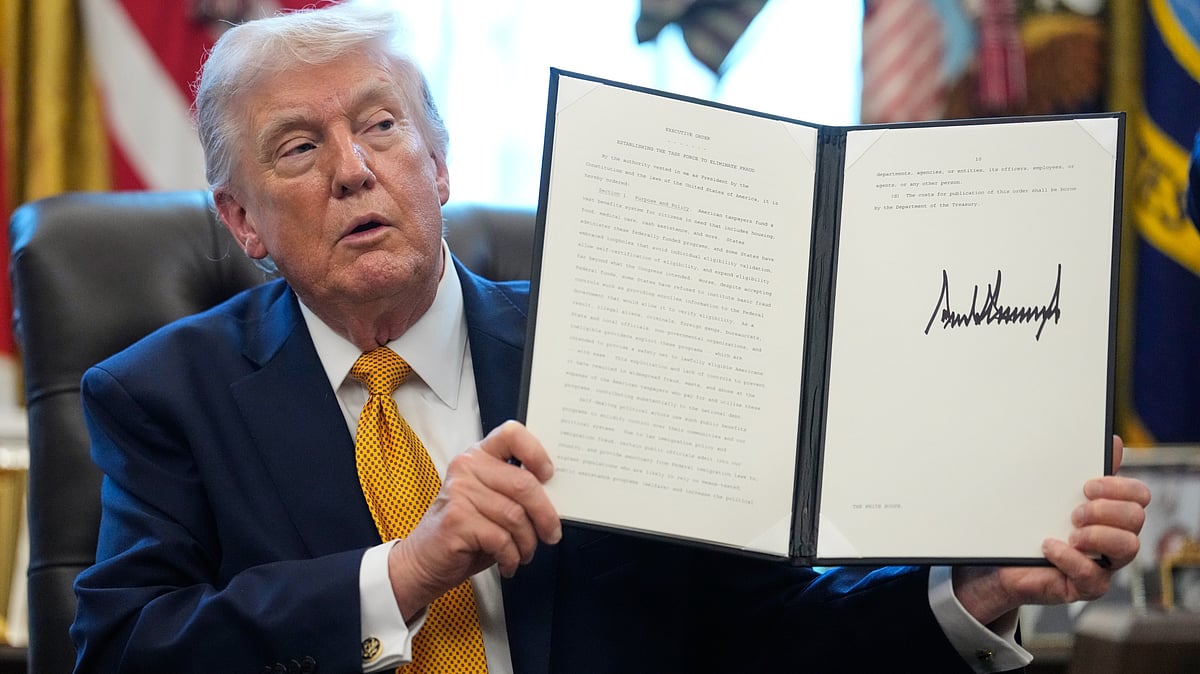 Donald Trump holds a signed executive order at Oval Office.