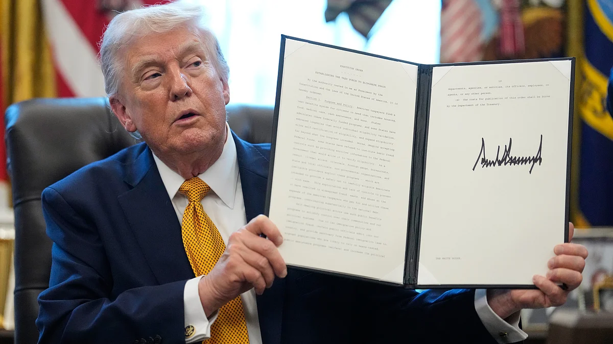 Donald Trump holds a signed executive order at Oval Office.