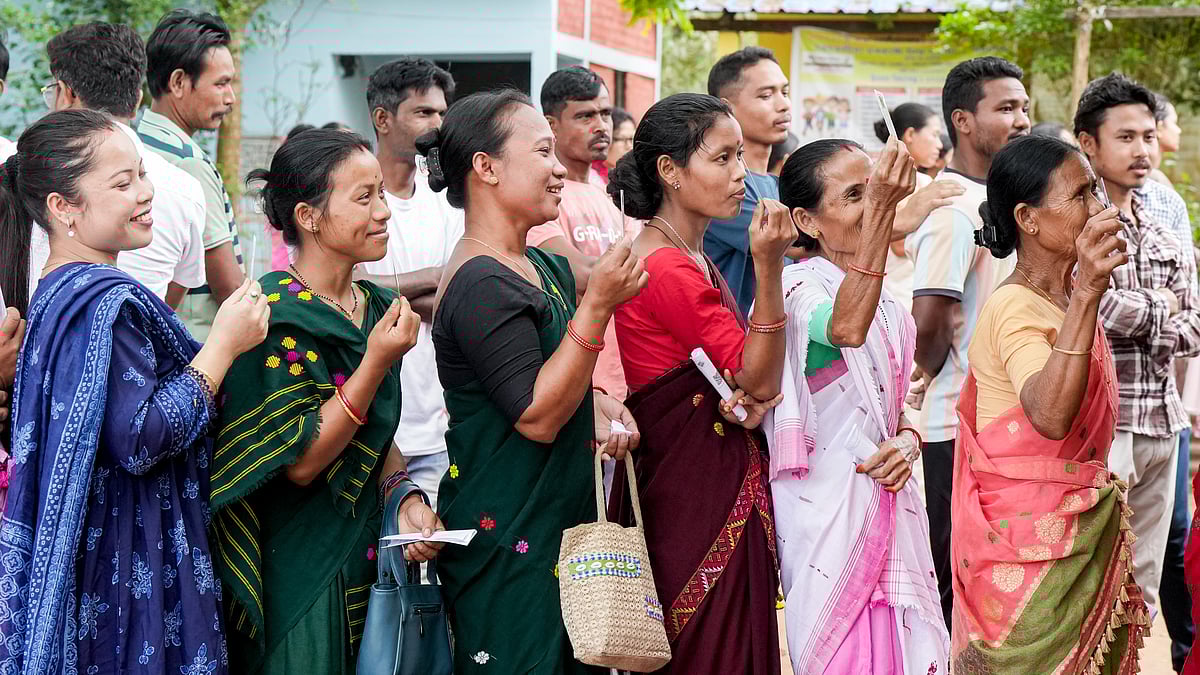 People wait in a queue to cast their votes in Assam's Kamrup district.