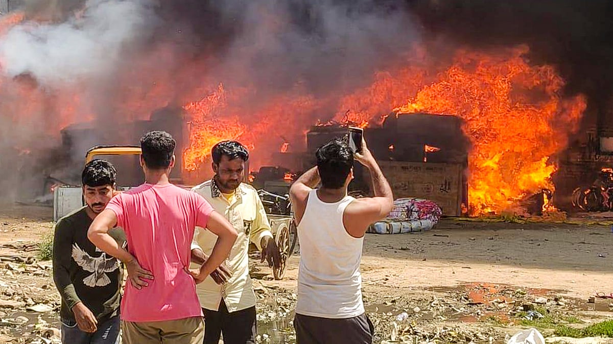 Flames engulf shanties as people look on after a fire broke out in a slum cluster in Sector 51, Gurugram.