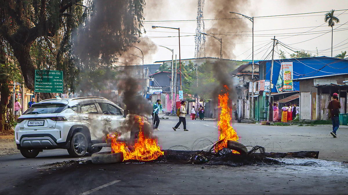 Protesters burn tyres and block a road near Bishnupur District Hospital.