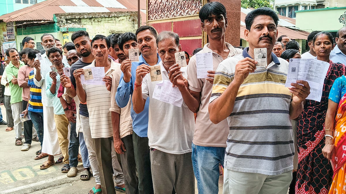 Voters stand in a queue to cast their votes at a polling booth in Habibpur,  Malda