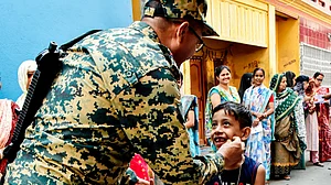 A security official with a young boy at a polling station in West Bengal's Murshidabad district
