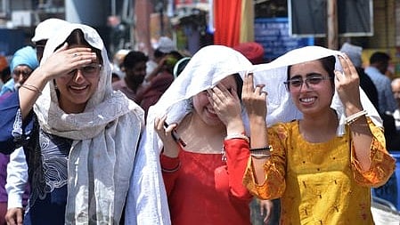 Women shield themselves from the blazing sun amid soaring temperatures.