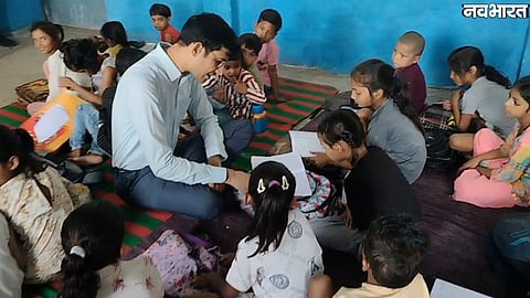 Morena Collector sits on floor with students and checks answer sheets