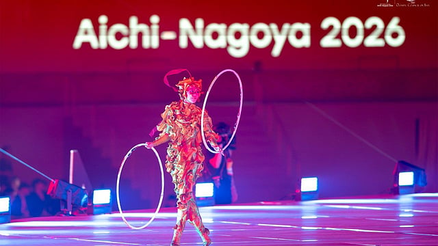 An artist wearing an intricate, textured gold-and-green costume