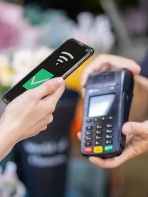 A woman uses her phone to make contactless payments