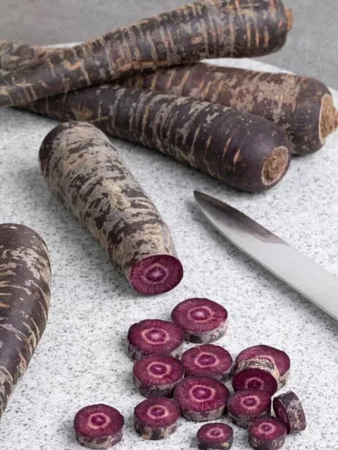 Purple carrot and slices on a cutting board close up