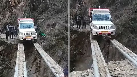 A viral video shows a Mahindra Bolero Pikup carefully crossing a deep trench on metal pipes in a mountainous area.