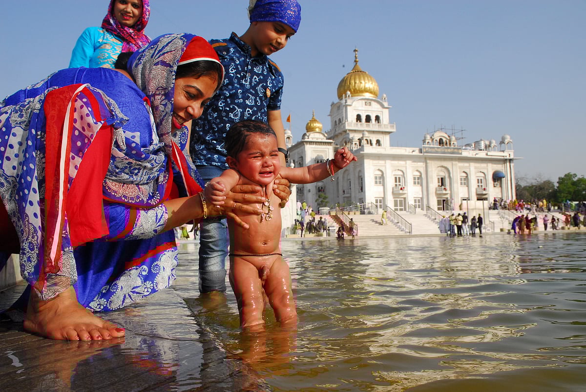 

दिल्ली के बंगला साहिब गुरुद्वारा में बैसाखी पर नहलाया जाता एक बच्चा