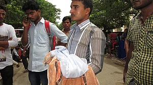 गोरखपुर के बीआरडी अस्पताल में मासूम का शव ले जाते परिजन / फोटो : Getty Images