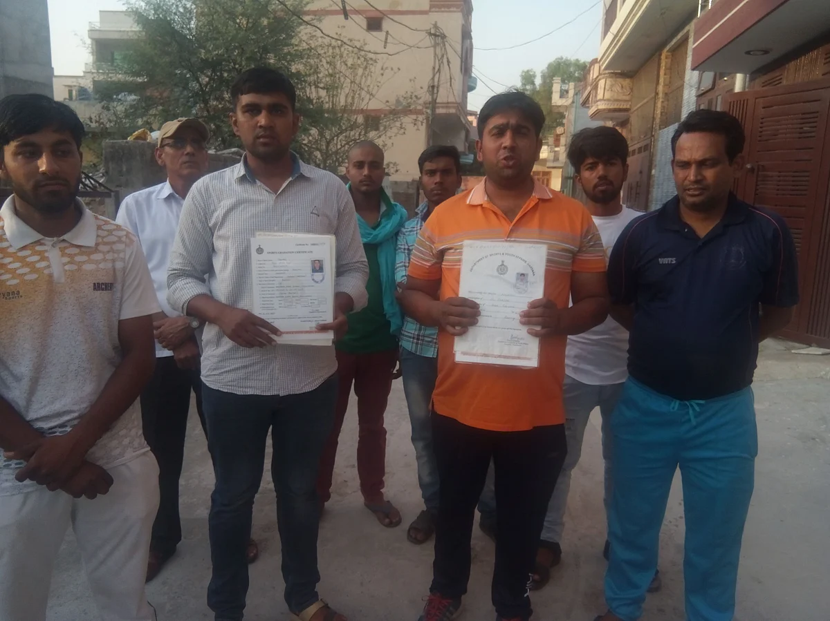 खेलों में पदक जीतने वाले युवा अपने सर्टिफिकेट दिखाते हुए