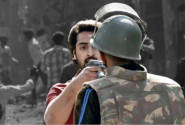 यह तस्वीर भी दिल्ली दंगों की है, जिसमें लाल टी-शर्ट पहने युवक पुलिस वाले पर पिस्तौल ताने है। बाद में इसकी पहचान शाहरुख के रूप में हुई