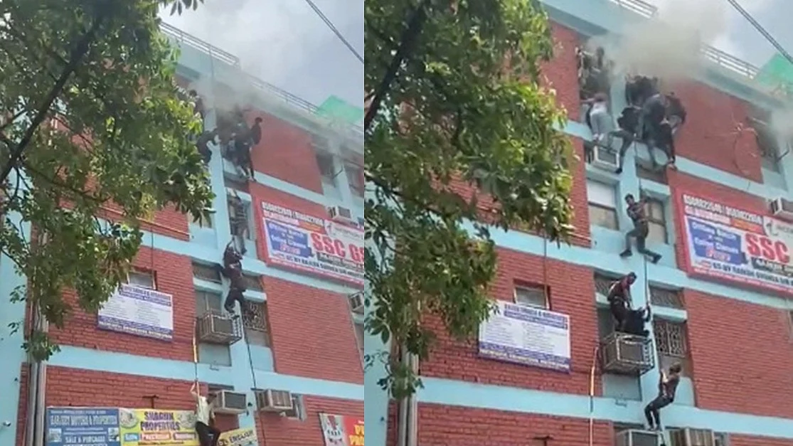 ये तस्वीर मुखर्जी नगर की है, जहां अग्निकांड के बाद बच्चे रस्सी के सहारे जान बचाने के लिए नीचे उतर रहे हैं। फोटो: IANS