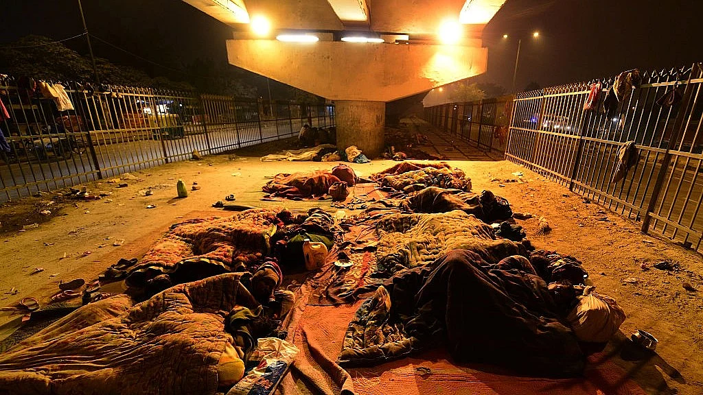 दिल्ली में सराय कालेखां बस अड्डे के नजदीक फ्लाईओवर के नीचे रात गुजारते लोग (फोटो : Getty Images)