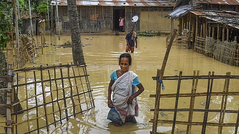 A woman walks through a flooded area in Nagaon district of Assam.