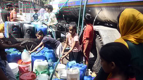 People are filling water in plastic drums from  a municipality tanker during a high temperature heat wave, in New Delhi.