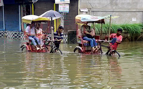 Rickshaw pullers wade through Assam floods